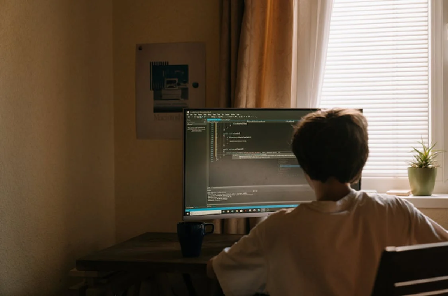 Boy sitting in white tshirt in front of computer